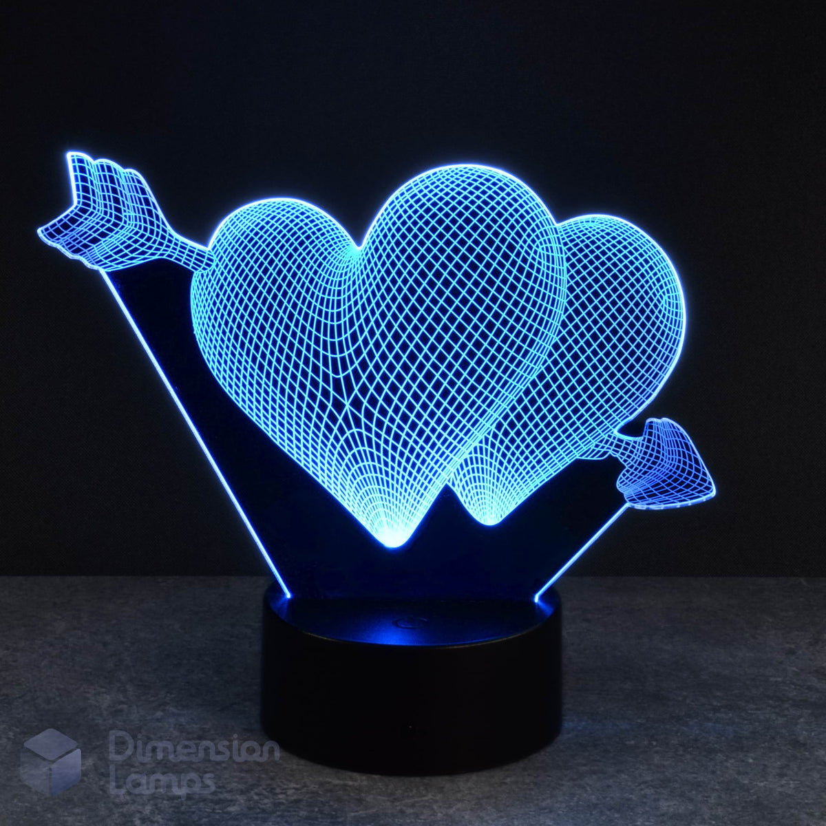 A cyan LED light forms the shape of two hearts connected and pierced by an arrow in this 3D lamp, set against a dark backdrop. This lamp offers a unique and eye-catching lighting option, a lovely present for girls bedrooms in Australia.
