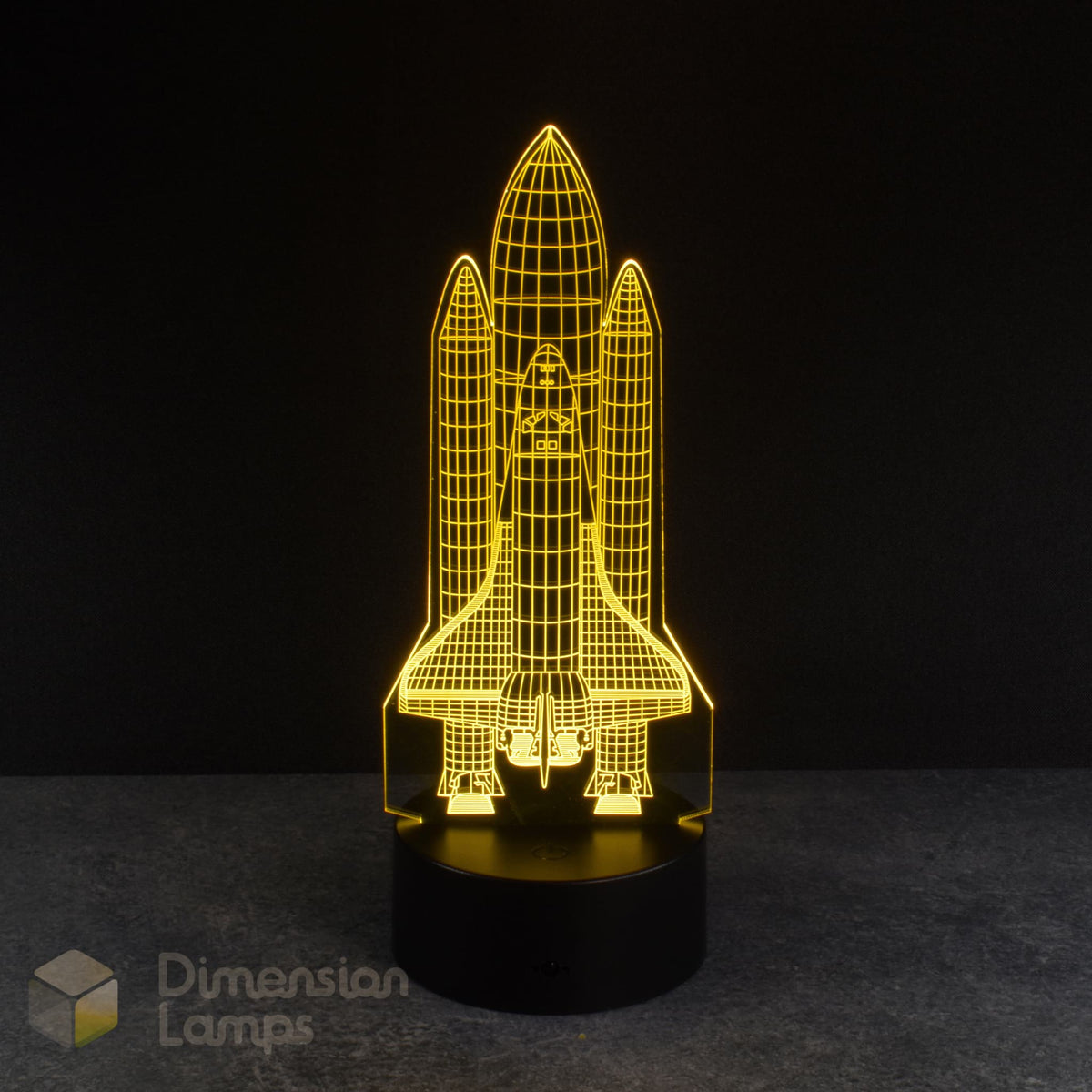 A yellow 3D lamp displays an etched design of a space shuttle, illuminated on a black base against a dark backdrop. An awesome nightlight for boys rooms across Australia.