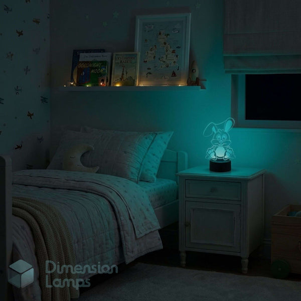 A glowing rabbit-shaped night light on a bedside table in a dimly lit child's bedroom, casting a cyan glow with a bed, shelf, books, and framed art.