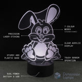 A 3D acrylic rabbit-shaped night light glowing on a black base, with text callouts highlighting features such as laser etching, clear acrylic display, sturdy plastic base, touch sensor operation, dual-power battery, and 7 colour modes. The brand name 'Dimension Lamps' appears in the bottom right corner.
