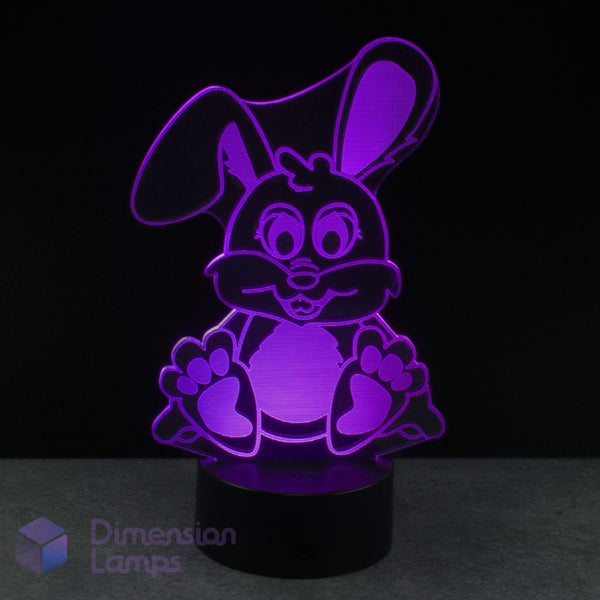 An LED 3D illusion lamp bunny night light glowing with purple light, set against a dark background. Gift idea for kids that like cute bunny rabbits.