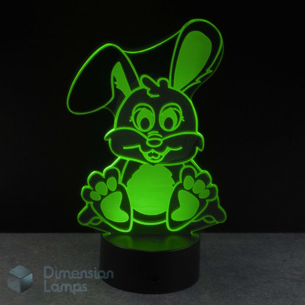 An LED 3D lamp of a cartoon bunny, glowing bright green against a black background. A Dimension Lamps watermark is visible in the bottom-left corner.