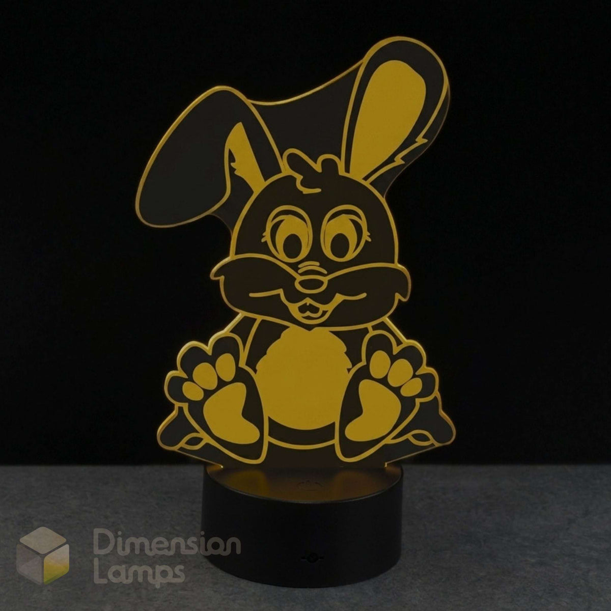 A 3D acrylic LED night light shaped like a cartoon bunny, featuring a yellow design on a black cylindrical base, set against a dark background.