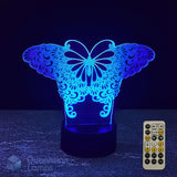 A 3D optical illusion LED night light shaped like a butterfly, glowing with blue light on a black base, shown with a 7 colour sleep timer remote control on a dark textured surface.