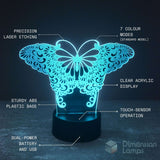 A butterfly-shaped LED night light with laser-cut ornamental patterns on a black cylindrical base, shown glowing in cyan-blue light against a dark background. White text callouts label features such as precision laser etching, 7 colour modes, clear acrylic display, sturdy ABS plastic base, touch-sensor operation, and dual-power battery and USB.
