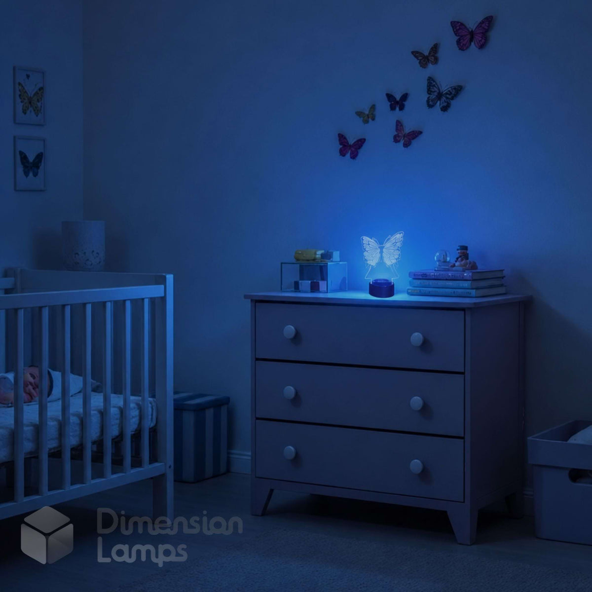 A softly glowing blue butterfly 3D illusion LED night light sits on a nursery dresser, casting a gentle ambient glow across a calm baby bedroom with butterfly wall decorations, books, toys, and a white cot.