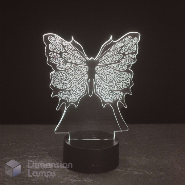 A butterfly-shaped LED night light with intricate wing patterns, glowing with a white light on a black cylindrical base, set against a dark background.