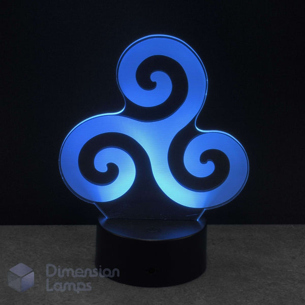 A 3D optical illusion LED night light with a glowing cyan triskelion symbol on a black base, set against a dark background. Triadic Life Cycles: Birth, life, and death or past, present, and future.