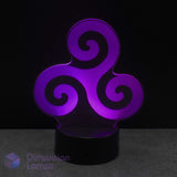 A 3D optical illusion night light featuring a glowing purple Celtic triskelion symbol on a black base, set against a dark background. Representing natural elements; earth, water, and sky.