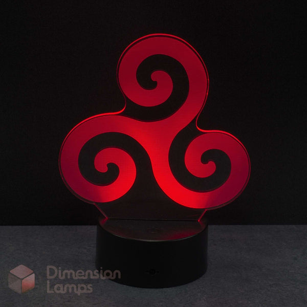 A red 3D optical illusion LED night light with a triskelion spiral design, resting on a black cylindrical base against a dark background. Celtic history gift idea. 