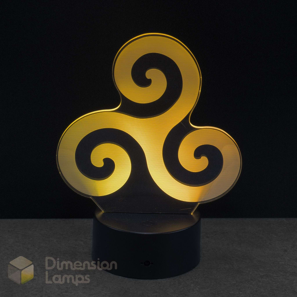 A 3D optical illusion LED night light with a yellow triskelion symbol on a black base against a dark background. Dimension Lamps watermark in the bottom-left. Mythology and Faith: Associated by some neopagans with the Triple Goddess or sea god Manannán mac Lir, and later reinterpreted by Christians to represent the Holy Trinity.