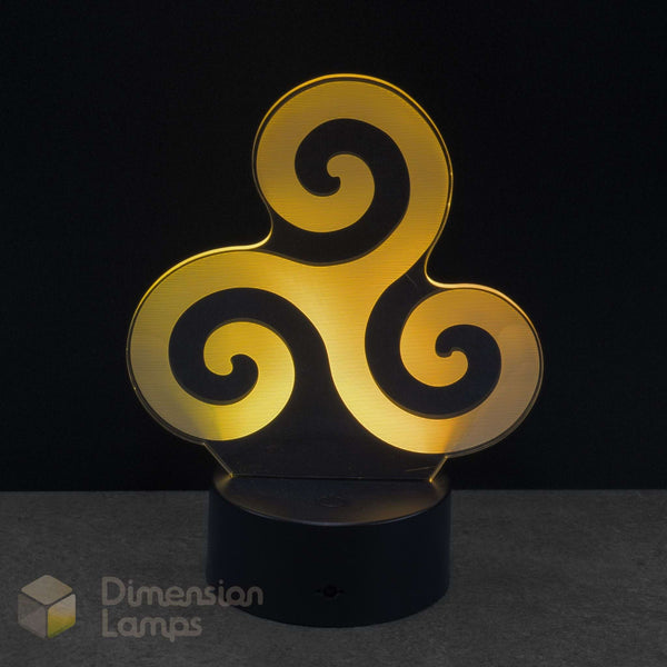 A 3D optical illusion LED night light with a yellow triskelion symbol on a black base against a dark background. Dimension Lamps watermark in the bottom-left. Mythology and Faith: Associated by some neopagans with the Triple Goddess or sea god Manannán mac Lir, and later reinterpreted by Christians to represent the Holy Trinity.