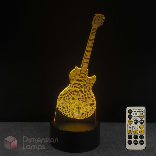 A 3D optical illusion LED night light of an electric guitar, glowing with a warm golden light, shown on a dark grey surface against a black background with a white remote control and a 'Dimension Lamps' logo watermark. Music teacher guitar gift.