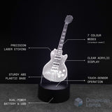 A 3D optical illusion LED night light shaped like an electric guitar, shown illuminated on a black base against a dark background, with white text callouts highlighting features such as laser etching, acrylic display, sturdy plastic base, touch sensor, and dual power.