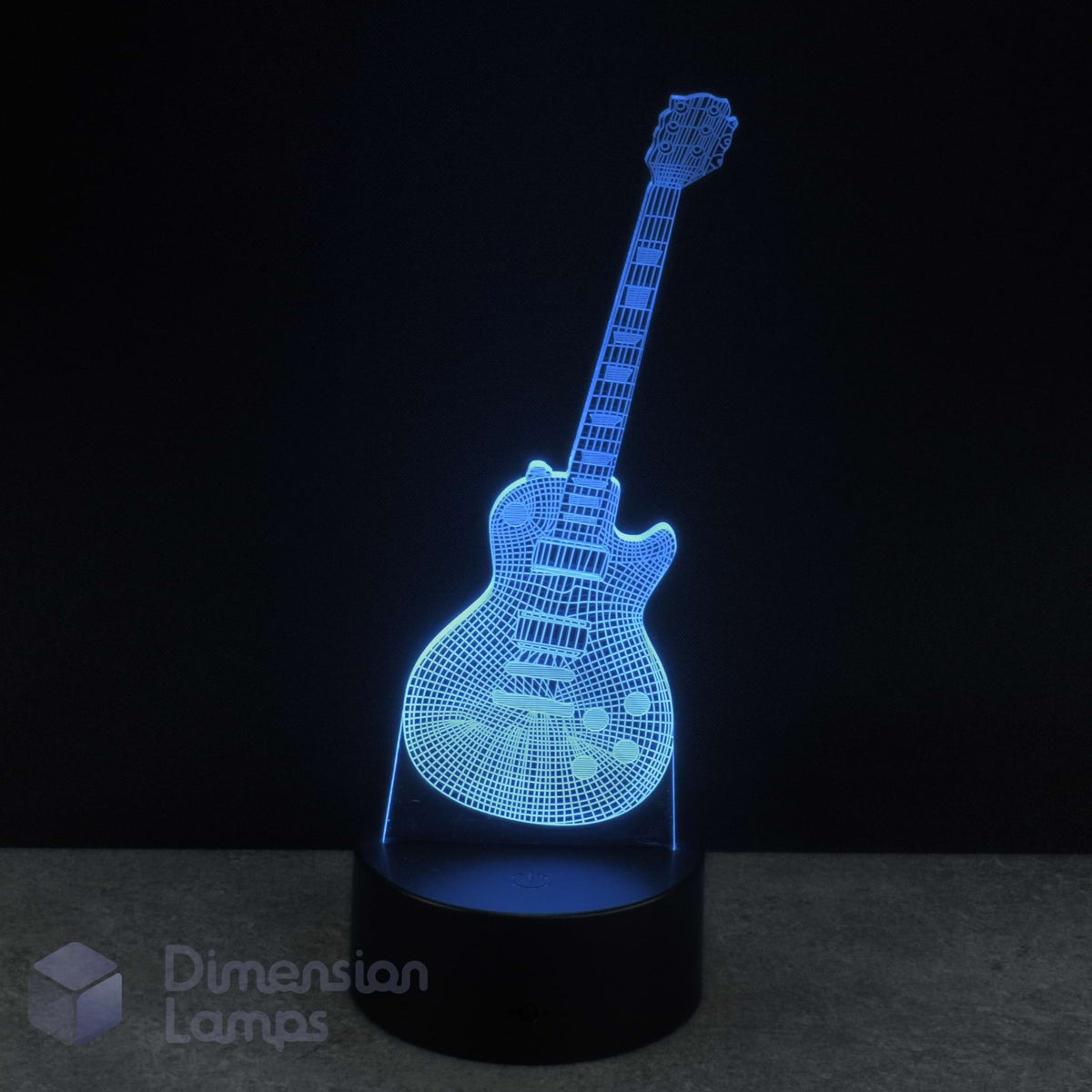 A 3D optical illusion lamp shaped like an electric guitar, glowing with a blue LED light on a black base against a dark background. A watermark for 'Dimension Lamps' in the bottom-left corner. Guitarist gift idea.