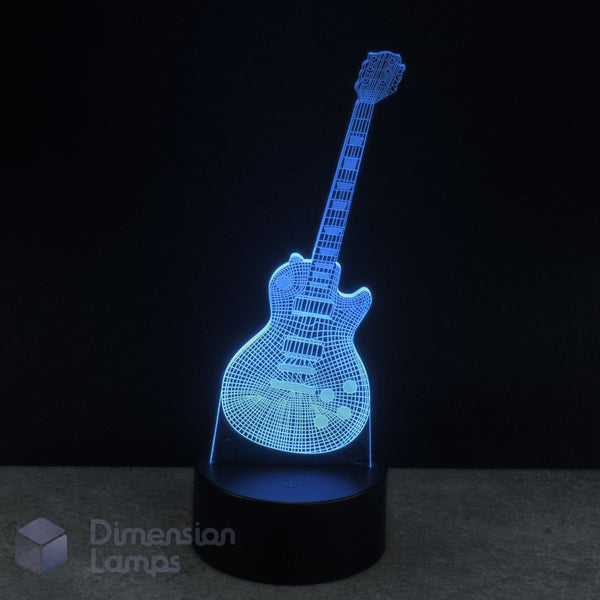 A 3D optical illusion lamp shaped like an electric guitar, glowing with a blue LED light on a black base against a dark background. A watermark for 'Dimension Lamps' in the bottom-left corner. Guitarist gift idea.