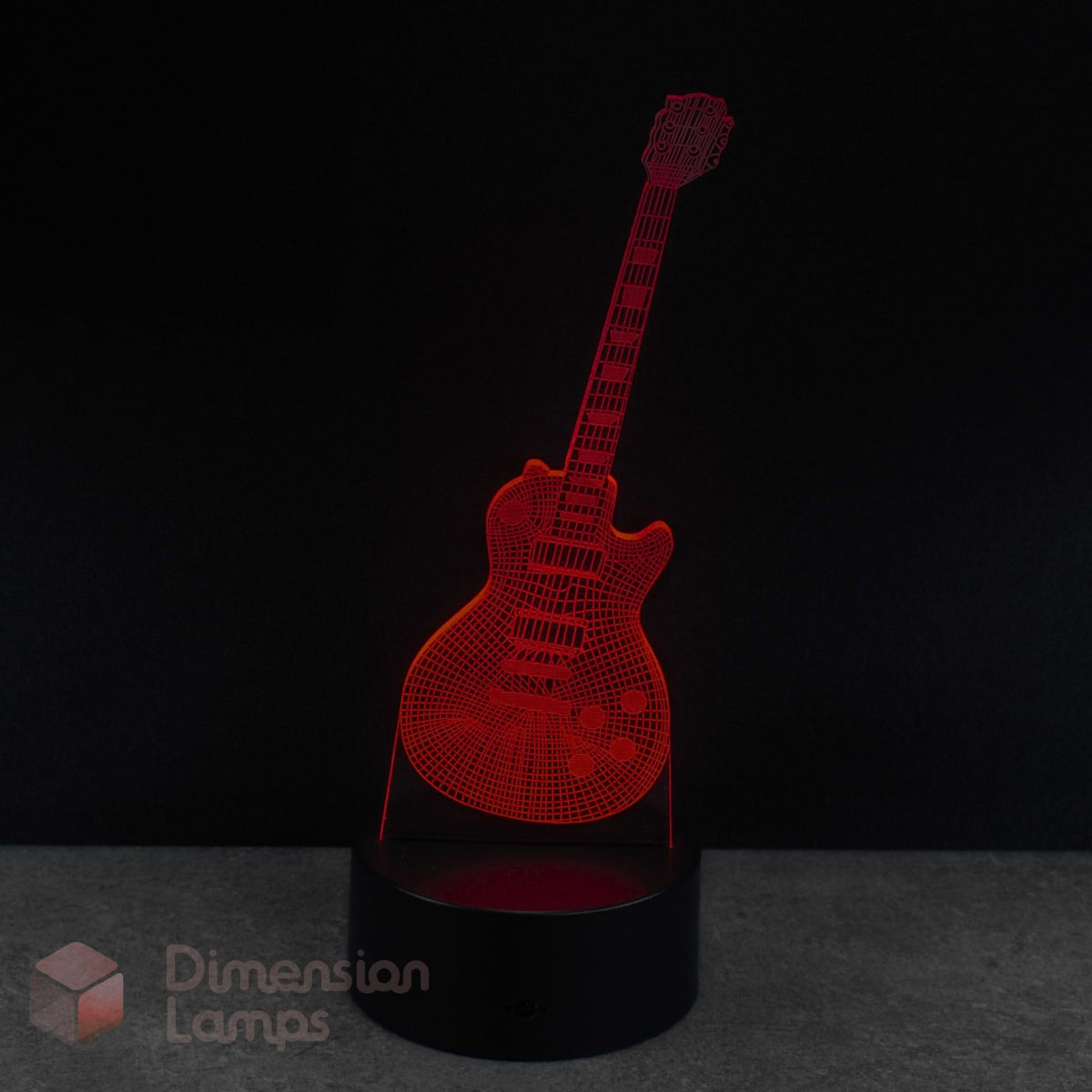 A red 3D optical illusion LED lamp shaped like an electric guitar, standing on a black cylindrical base against a dark background. The brand name 'Dimension Lamps' is visible as a watermark in the bottom-left corner.