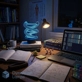 A glowing cyan 3D DNA strand LED night light on a desk next to a laptop, books, and a dimly lit study room. Dimension Lamps watermark in the corner.