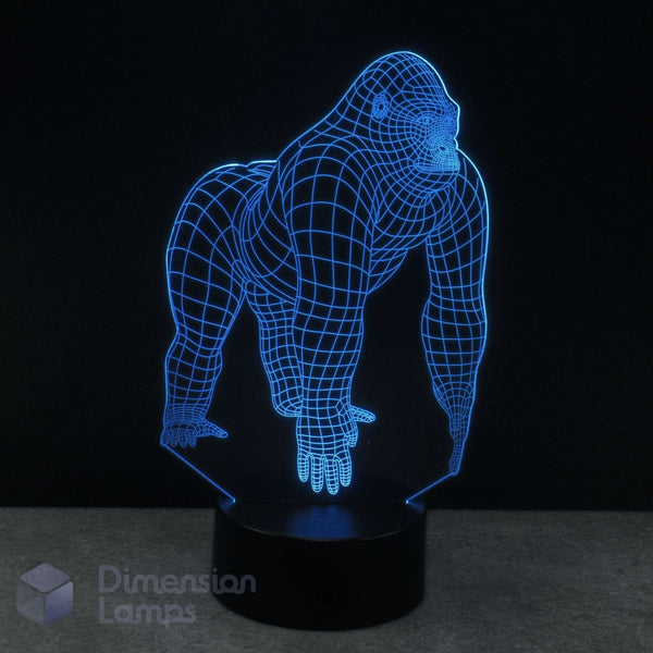 A 3D optical illusion lamp shaped like a gorilla, glowing with blue LED light on a black base with a dark background. Dimension Lamps gorilla gift. 