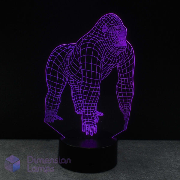 A purple wireframe gorilla-shaped 3D optical illusion LED night light on a black base against a dark background with a watermark in the lower-left.