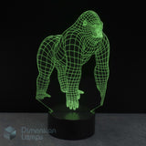 A 3D glowing with green gorilla wireframe illusion lamp on a black base with a dark background. Dimension Lamps watermark in the bottom-left corner.