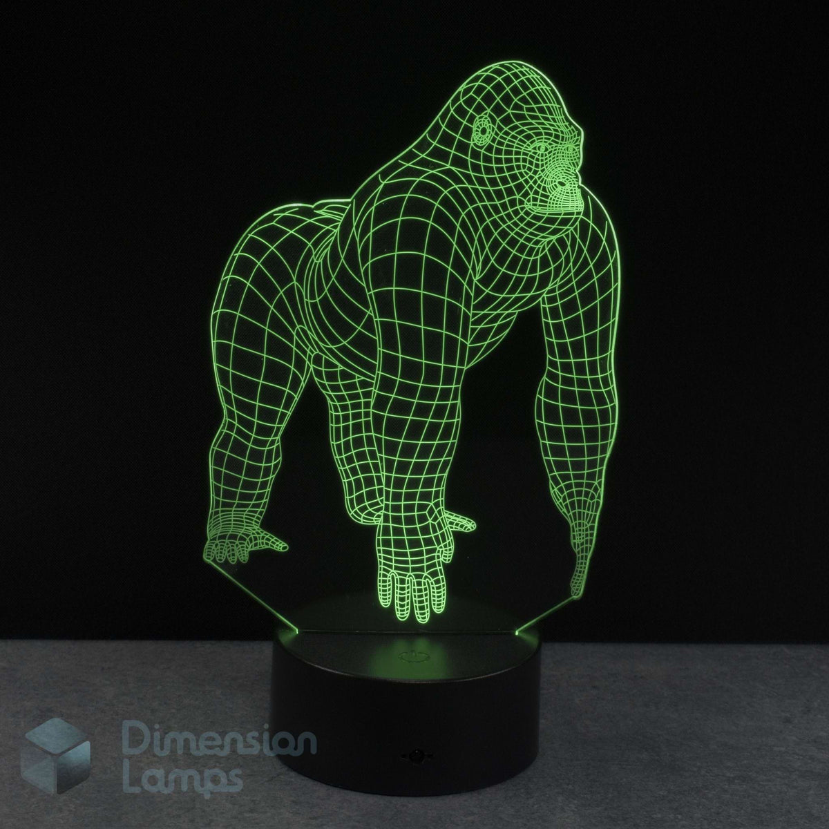 A 3D glowing with green gorilla wireframe illusion lamp on a black base with a dark background. Dimension Lamps watermark in the bottom-left corner.