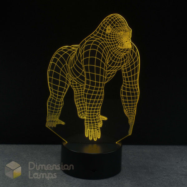 A 3D optical illusion LED lamp shaped like a gorilla, glowing with a yellow wireframe outline on a black base, set against a dark background.
