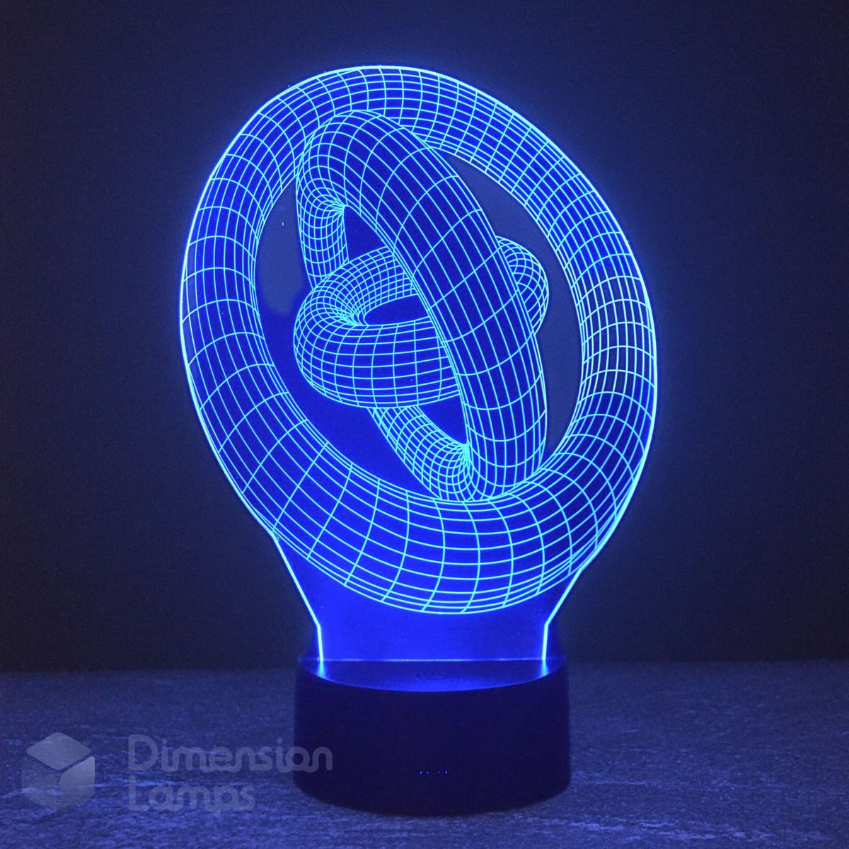 A 3D optical illusion LED night light shaped like a knot, glowing with a bright blue light on a dark base against a dark background. A 'Dimension Lamps' watermark is visible in the lower-left corner.