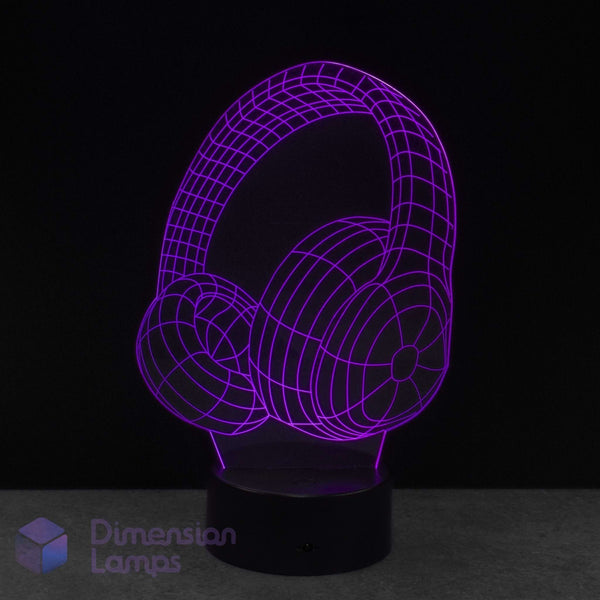 A 3D optical illusion LED lamp shaped like over-ear headphones, glowing with a purple wireframe effect on a black base against a dark background.