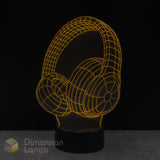 A 3D optical illusion lamp of over-ear headphones, glowing with a warm yellow wireframe outline on a black circular base. Teens music gift idea. 