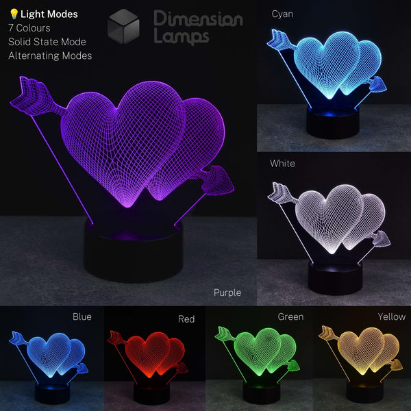 A 3D illusion LED lamp shaped like two interlocking hearts with arrows, shown in multiple color modes on a dark background. The left large panel shows the lamp lit in purple, with smaller panels showing other available colors: cyan, white, blue, red, green, and yellow.