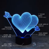 A 3D illusion LED lamp shaped like two interlocking hearts pierced by arrows, glowing in blue light on a black base. White text callouts highlight features such as 7 colour modes, clear acrylic display, precision laser etching, sturdy ABS plastic base, touch-sensor operation, dual-power battery & USB, and the Dimension Lamps brand.