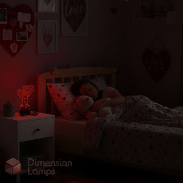 A child's bedroom scene in very low light showing a bed with a child tucked in, a bedside table with a glowing heart-shaped lamp, and heart-themed wall decorations. The watermark 'Dimension Lamps' appears in the lower left.