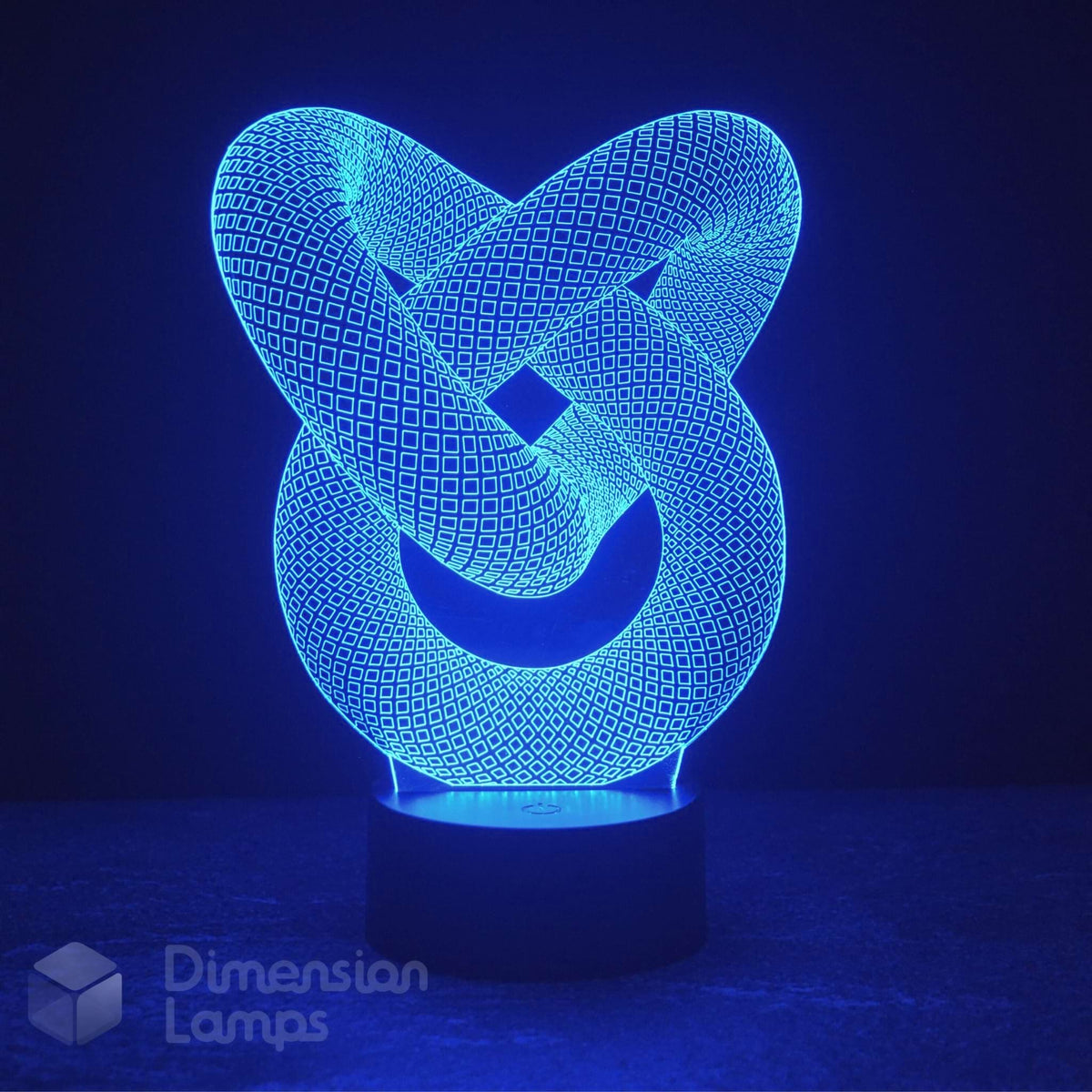 A 3D optical illusion LED night light shaped like an interlocking knot, glowing with a bright blue light on a dark base against a dark blue background. A 'Dimension Lamps' logo watermark is visible in the bottom-left corner.