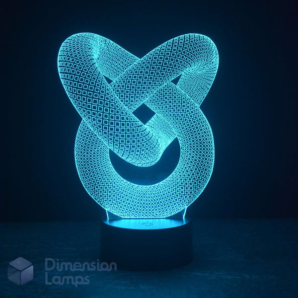 A 3D optical illusion LED night light shaped like an interlocking knot, glowing with a bright cyan-blue light on a dark base against a dark background. A 'Dimension Lamps' logo watermark is visible in the bottom-left corner.