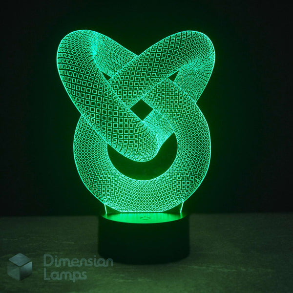 A 3D optical illusion LED lamp featuring an interlocking knot design that glows with a vibrant green light, set on a black cylindrical base against a dark background.