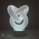 A 3D optical illusion LED night light shaped like an interlocking knot, glowing with a white light on a dark base against a dark background. A 'Dimension Lamps' logo watermark is visible in the bottom-left corner.