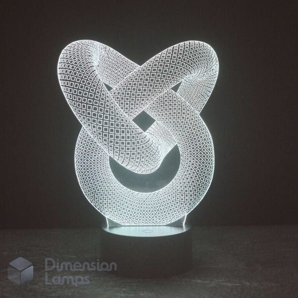 A 3D optical illusion LED night light shaped like an interlocking knot, glowing with a white light on a dark base against a dark background. A 'Dimension Lamps' logo watermark is visible in the bottom-left corner.