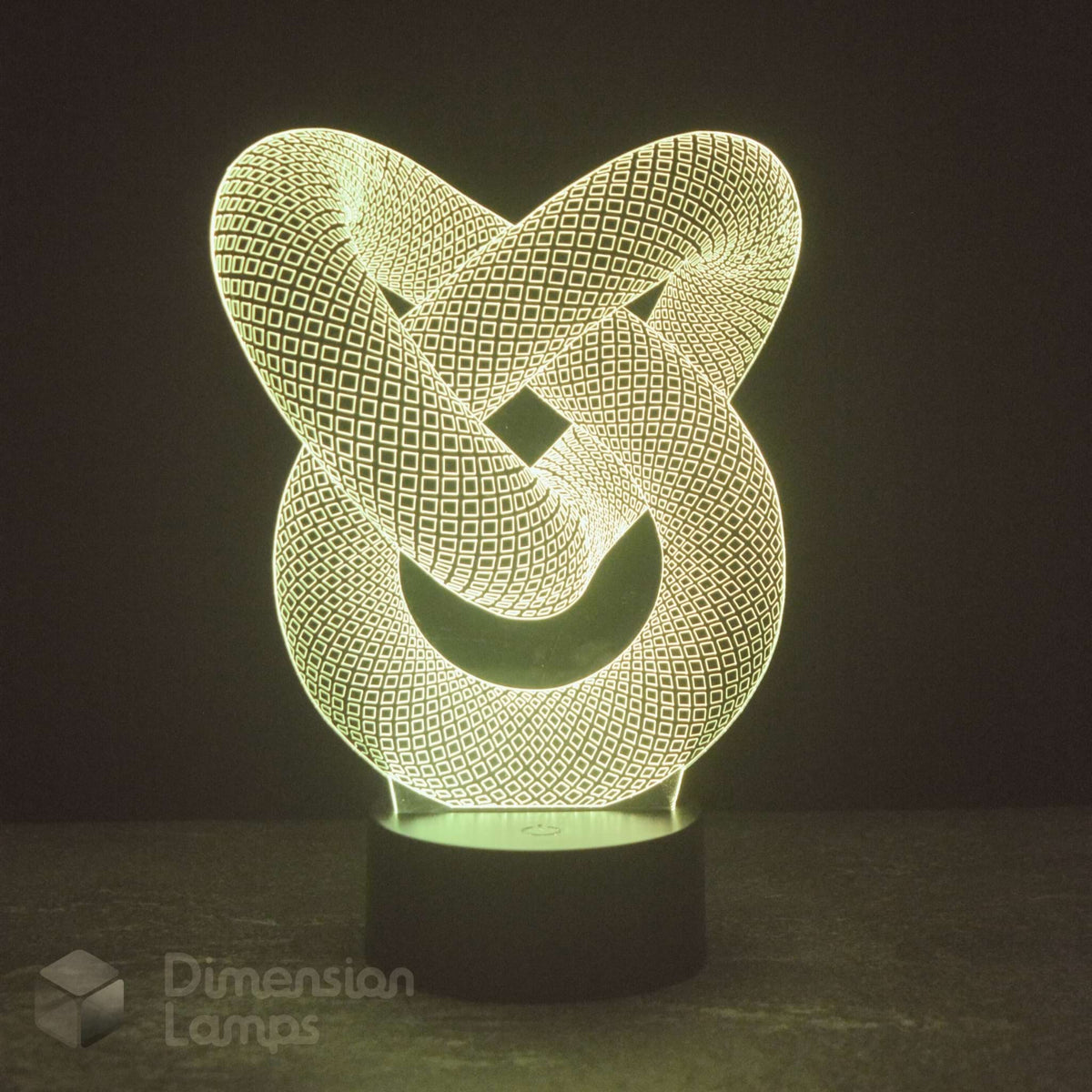 A 3D optical illusion LED night light shaped like an interlocking knot, glowing with a warm yellow-green light on a dark base against a dark background.