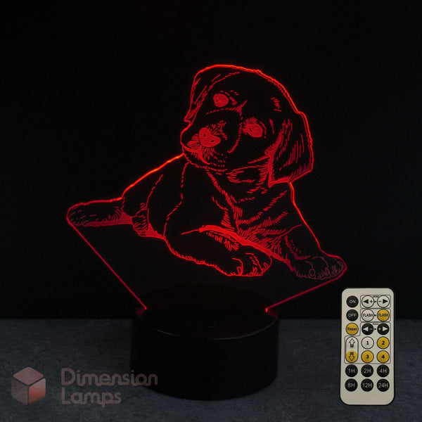 A red LED light-up lamp shaped like a puppy sitting on a black base, shown against a dark background with a white remote control and a 'Dimension Lamps' logo watermark.