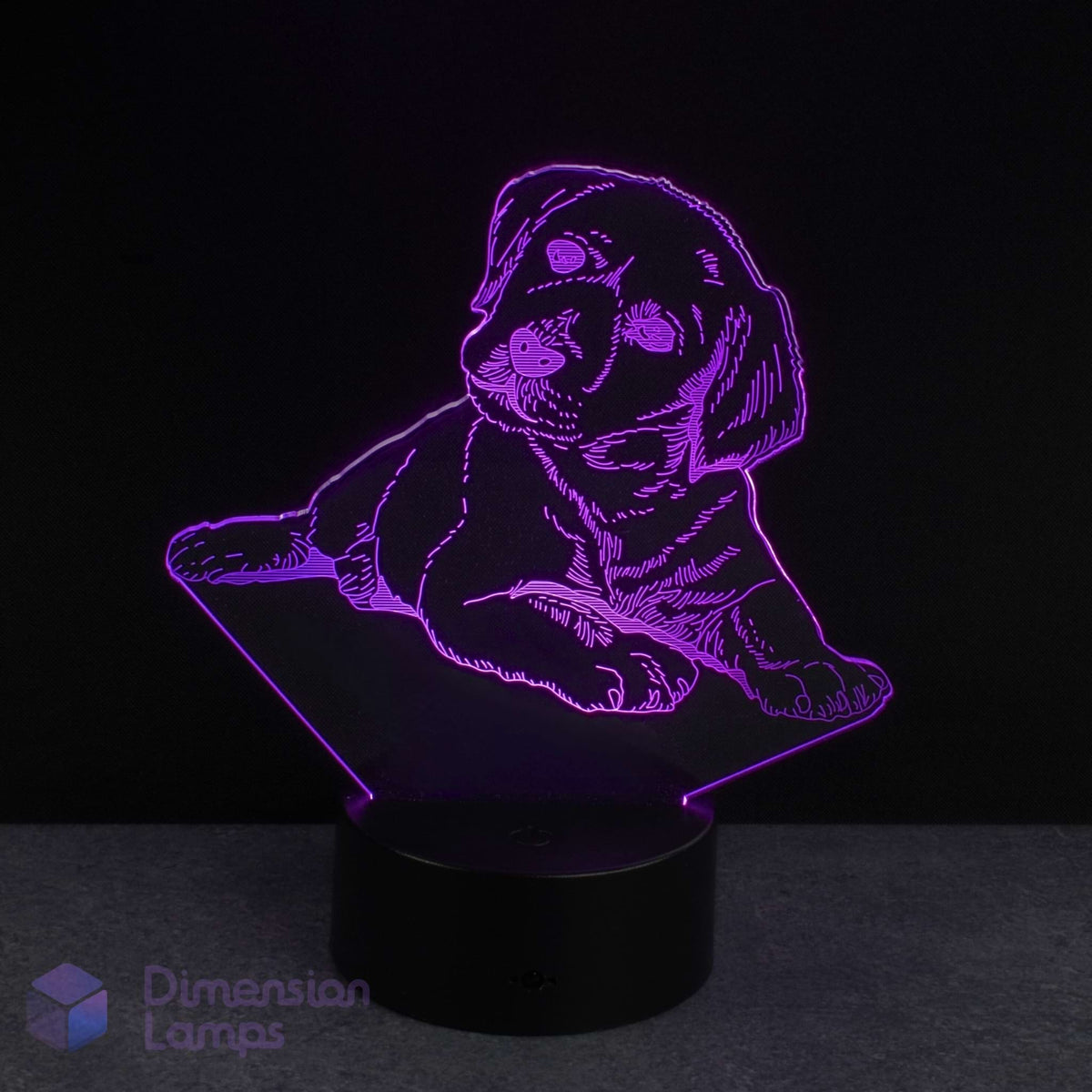 A 3D optical illusion LED night light shaped like a puppy, glowing with a purple light on a black base against a dark background. A 'Dimension Lamps' watermark is visible in the bottom-left corner.
