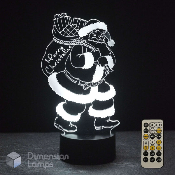 A glowing white Santa Claus 3D LED night light carrying a Christmas sack with 'Merry Christmas' written on it, on a black base with a remote control.