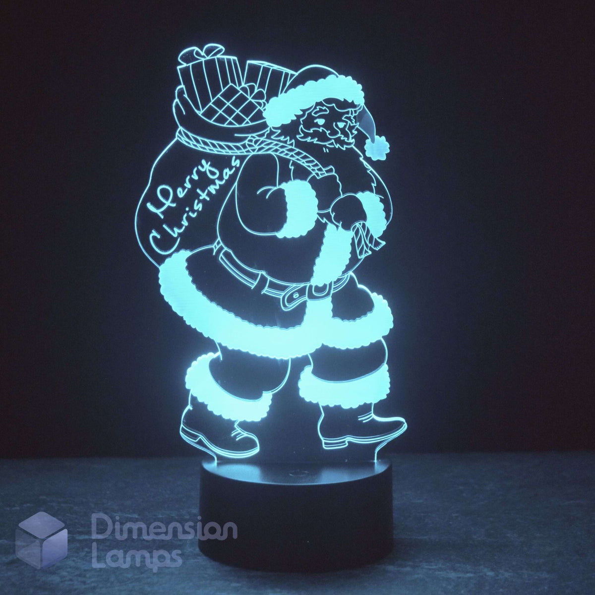 An LED 3D lamp of Santa Claus carrying a Christmas sack with 'Merry Christmas' written on it, set against a dark background. Xmas décor lighting idea.