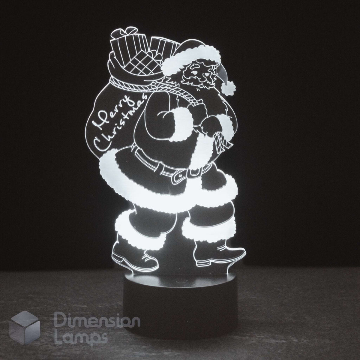 A glowing white LED night light of Santa Claus carrying a Christmas sack, on a black base against a dark background. And the words 'Merry Christmas'.
