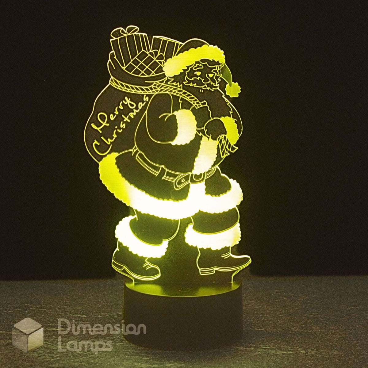 An LED 3D optical illusion night light of Santa Claus carrying a sack, glowing with a warm yellow light against a dark background. Christmas lighting.