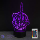 A purple 3D optical illusion night light shaped like a skeletal hand showing the middle finger, illuminated on a black base with a 16 colour remote control in the bottom right corner.