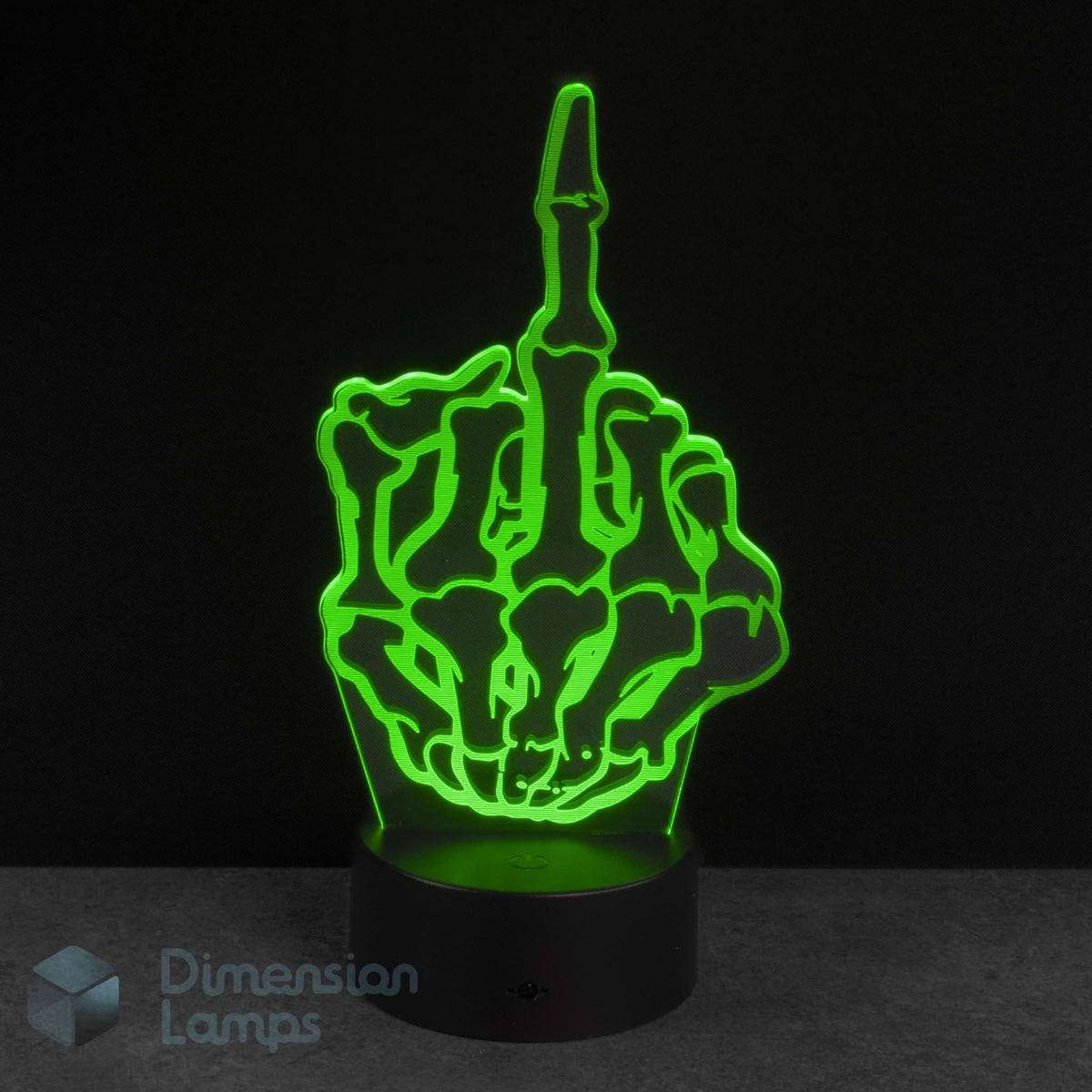 A 3D optical illusion LED night light shaped like a skeleton hand making the middle finger, glowing bright green on a black base against a dark background. Novelty young adult fun gift idea. 