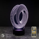 A 3D optical illusion LED night light with a glowing white wireframe mobius strip design on a black base, shown with its remote control on a dark grey surface against a black background. Sci-fi fan gift idea.