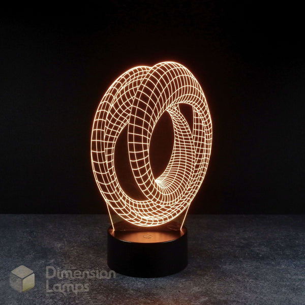 Mobius strip 3d night lamps: yellow illumination of a continuous looped geometric design on a lamp, rising from a base against a dark background. Marvel Avengers Endgame movie.