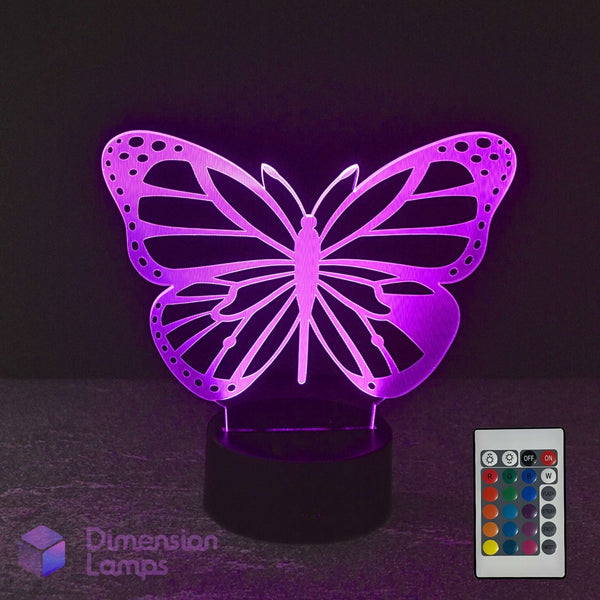 A butterfly-shaped 3D LED night light emitting a bright purple glow, shown on a black base with a 16 colour remote control in the bottom right corner. Girls butterfly gift. 